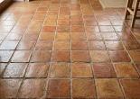 Square terracotta floor tiles in warm earthy tones arranged in a grid pattern